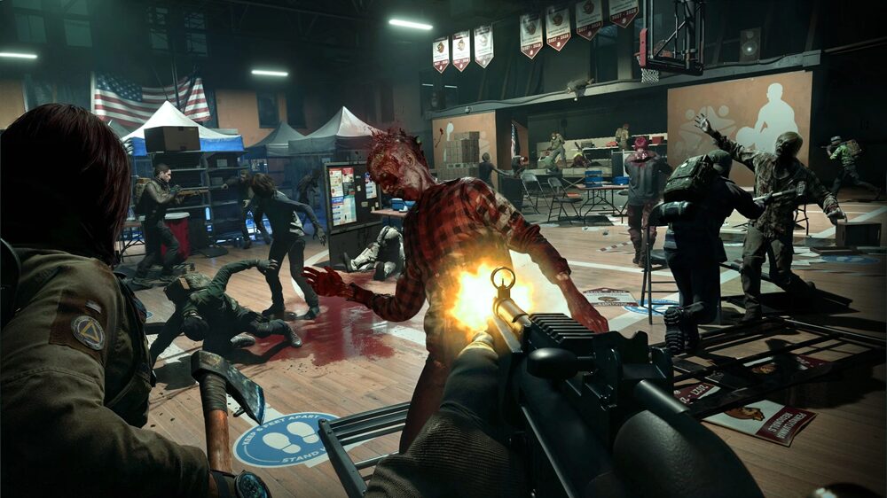 A first-person view inside a modern gymnasium showing the PoV character shooting a zombie at close range. Other uninfected humans are on his flanking sides, also helping to attack the zombies.